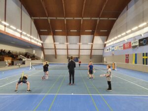barn tränar tennis i hall med bra belysning